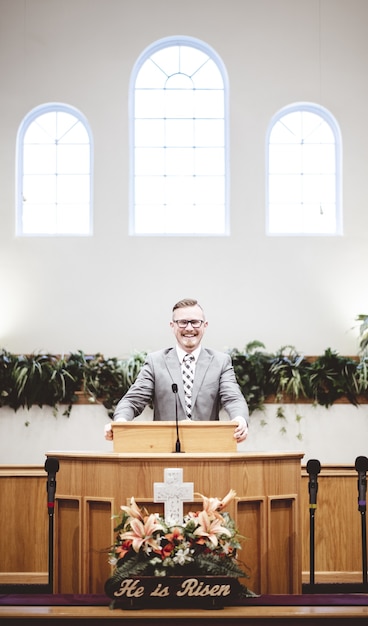 Mann in einem formellen Outfit, der die Heilige Bibel von der Tribüne am Altar der Kirche predigt