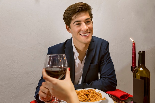 Mann in einem romantischen Abendessen, das mit Wein röstet