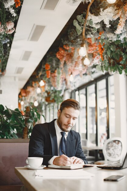 Mann in einem schwarzen Anzug. Männlich im Restaurant. Mann mit einem Computer.