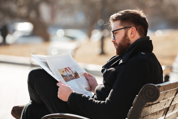 Mann in Gläsern sitzen und Zeitung in der Stadt lesen