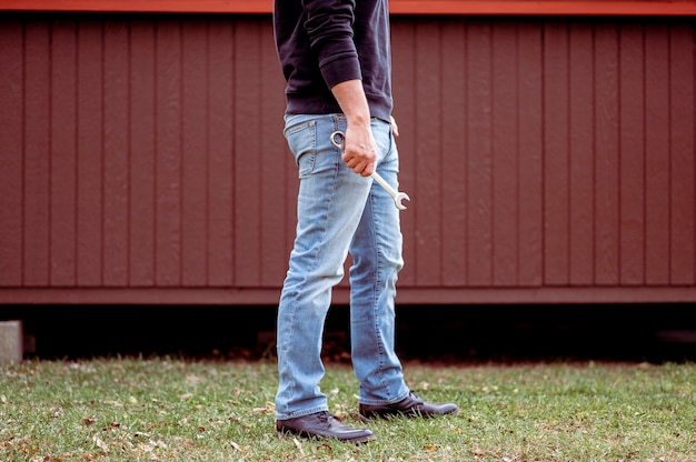 Kostenloses Foto mann in jeans hält einen schraubenschlüssel