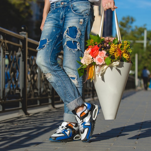 Mann in Jeans mit einem Pappblumenstrauß.