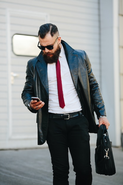 Mann in Leder Regenmantel sein Handy überprüft