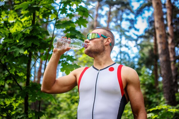 Mann in Sportbekleidung und Sonnenbrille mit Flasche Wasser.