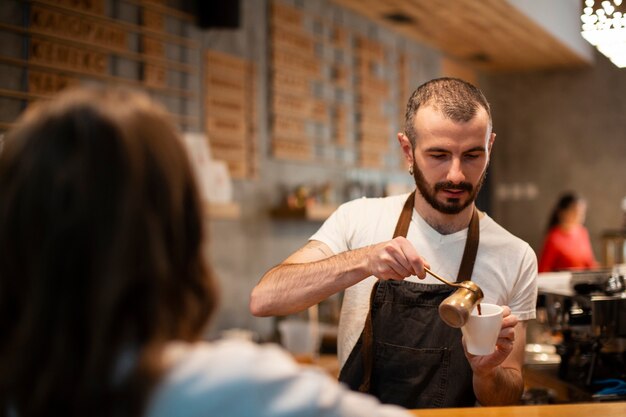 Mann in strömendem Kaffee des Schutzblechs in der Schale für Kunden