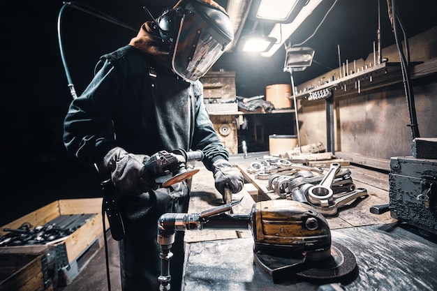 Mann in Uniform und Schutzmaske arbeitet in der Metallfabrik.