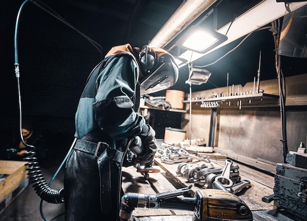 Mann in Uniform und Schutzmaske arbeitet in der Metallfabrik.