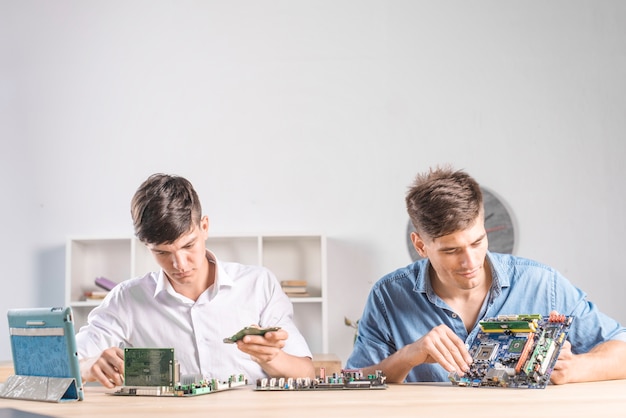 Kostenloses Foto mann it-techniker zwei, der das computer mainboard in der service-mitte überprüft