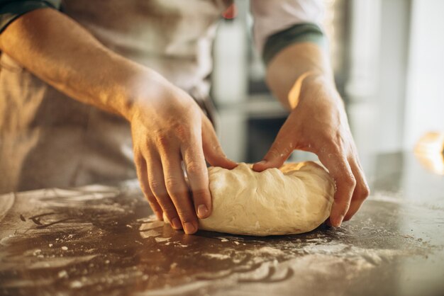 Mann knetet den Teig für Brot