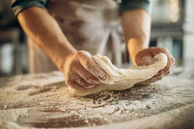 Mann knetet den Teig für Brot