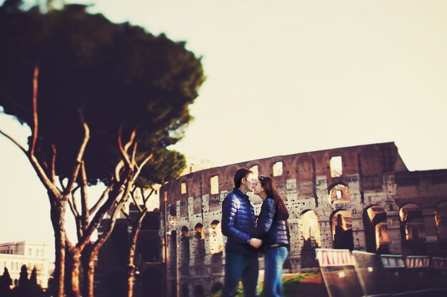 Mann küsst Frau in Nase vor dem Kolosseum