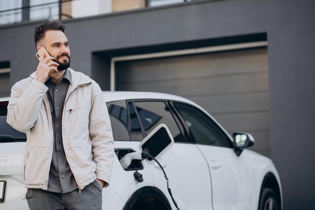 Mann lädt Elektroauto am Haus auf