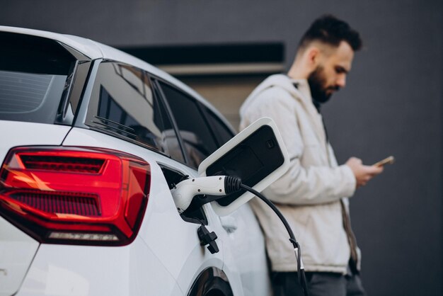 Mann lädt Elektroauto am Haus auf