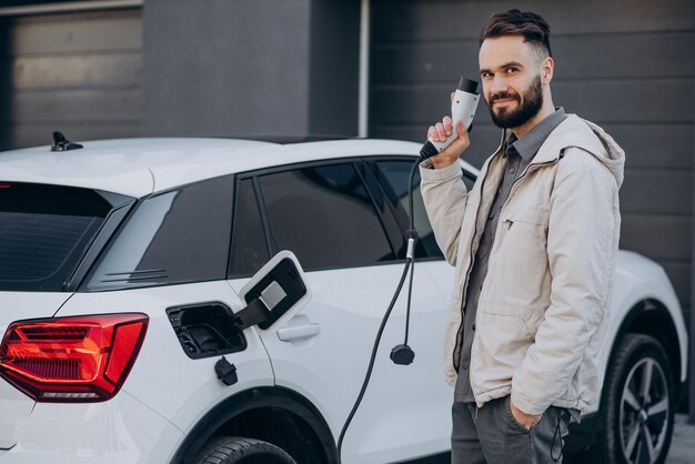 Mann lädt Elektroauto am Haus auf