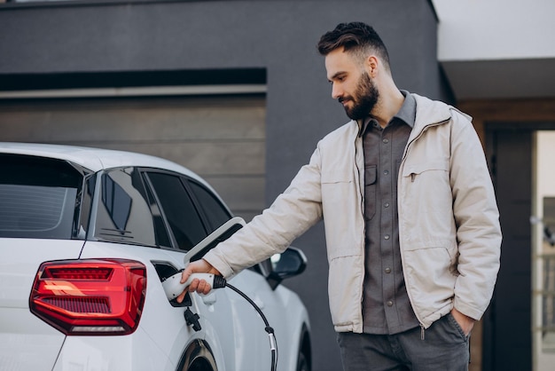 Mann lädt Elektroauto am Haus auf