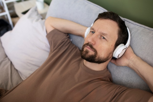 Mann liegt auf dem Bett und hört Musik