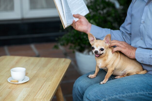 Mann liest zu Hause neben seinem Hund ein Buch