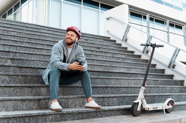 Kostenloses Foto mann macht eine pause, nachdem er seinen roller gefahren ist