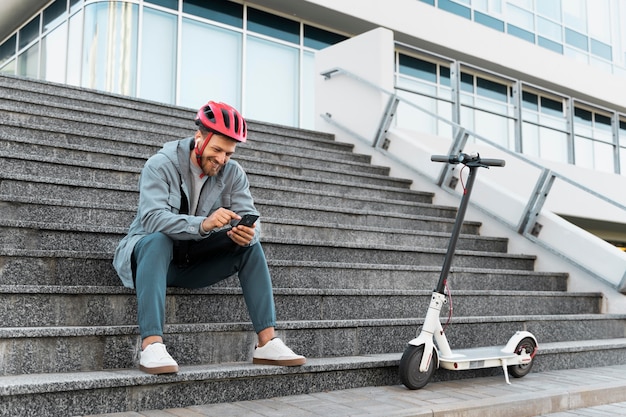 Mann macht eine Pause, nachdem er seinen Roller gefahren ist