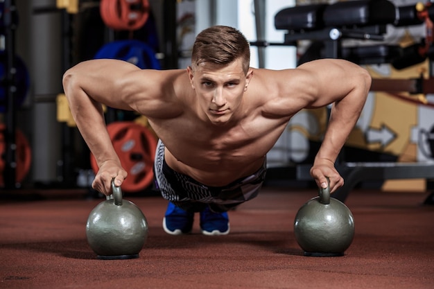 Kostenloses Foto mann macht liegestütze mit hantel im crossfit-fitnessstudio.