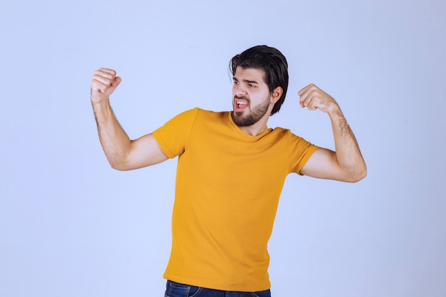 Mann mit Bart, der seine Faust- und Armmuskulatur demonstriert und sich mächtig fühlt
