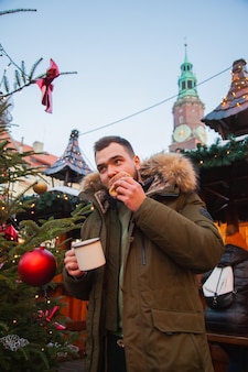 Mann mit becher getränk und trdelnik auf dem weihnachtsmarkt in breslau, polen