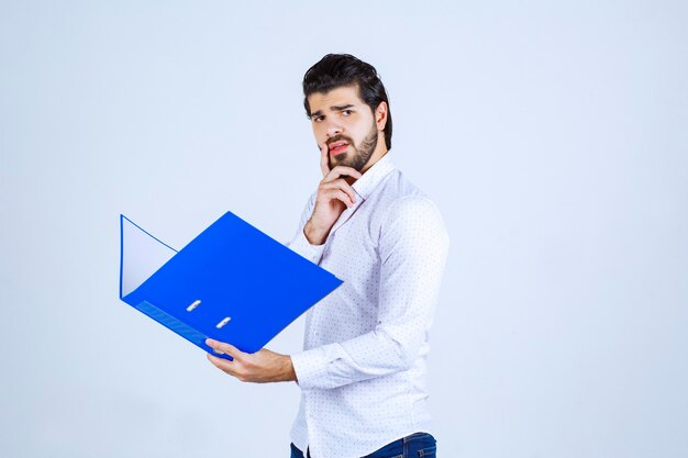 Mann mit blauem Ordner sieht erschöpft und unzufrieden aus