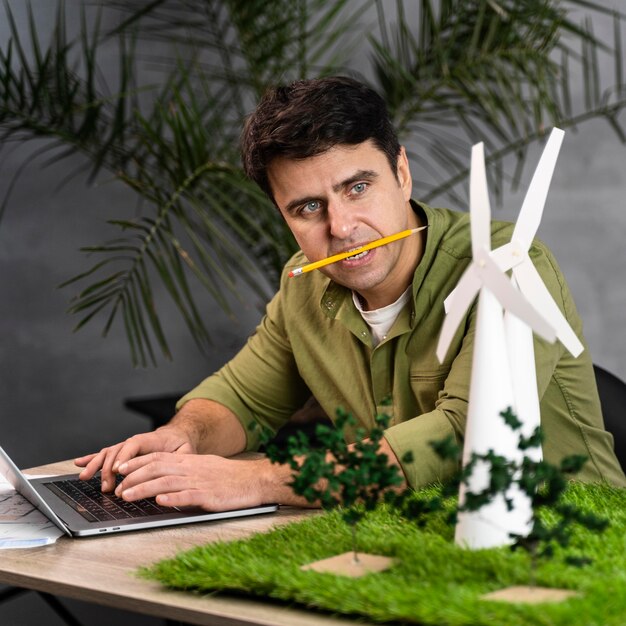 Mann mit Bleistift im Mund, der an einem umweltfreundlichen Windkraftprojekt arbeitet