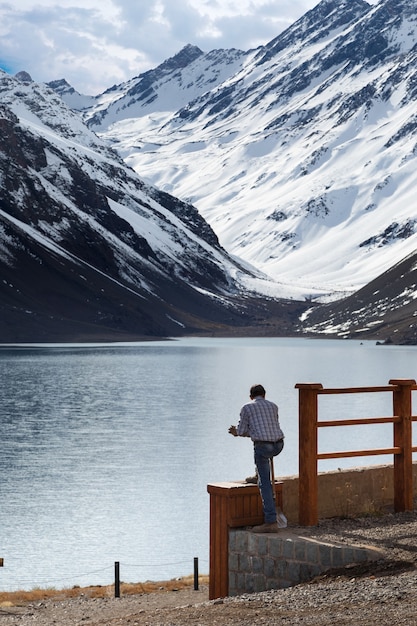 Kostenloses Foto mann mit blick auf den see laguna del inca, umgeben von bergen in chile