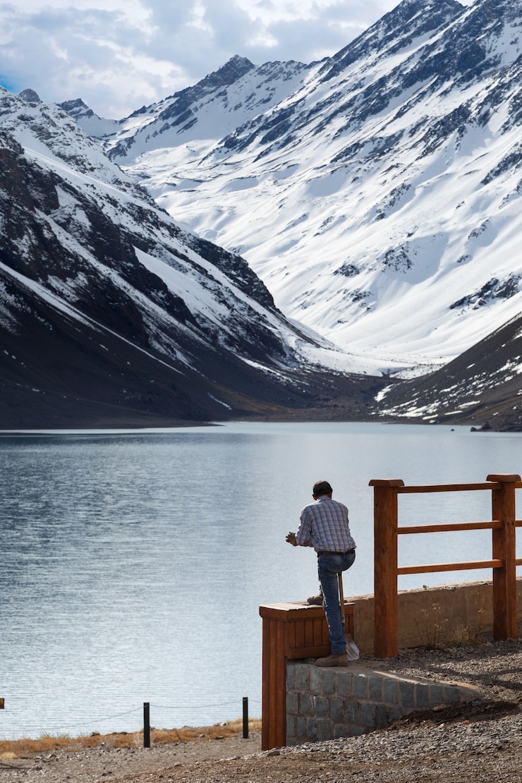Kostenlose Foto mann mit blick auf den see laguna del inca, umgeben von bergen in chile