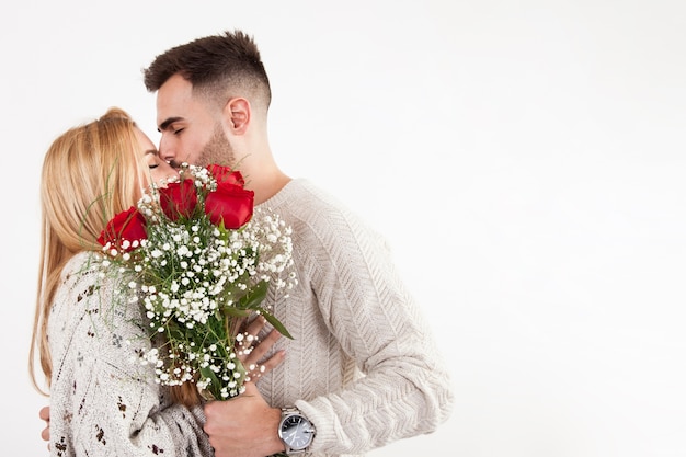 Kostenloses Foto mann mit blumenstrauß, der frau küsst