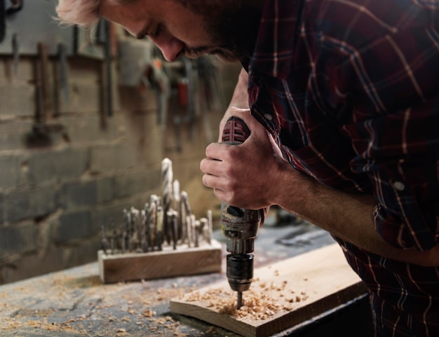 Mann mit Bohrer, der mit Holz arbeitet