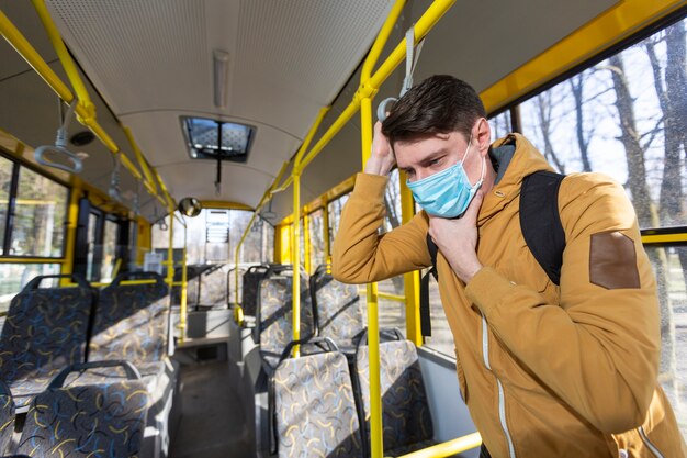 Mann mit chirurgischer Maske im öffentlichen Verkehr