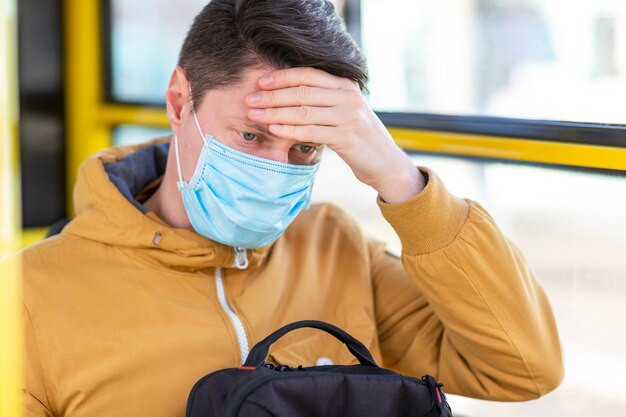 Mann mit chirurgischer Maske im öffentlichen Verkehr