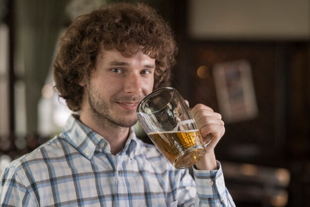 Mann mit dem Bier, das Kamera betrachtet