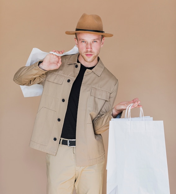 Mann mit dem braunen Hut, der die Einkaufstaschen hält