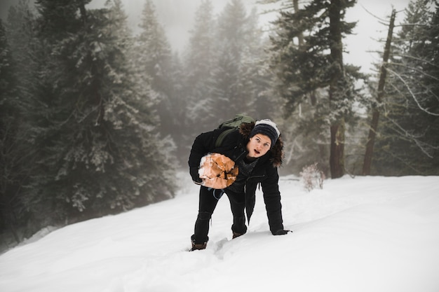 Mann mit dem Brennholz gehend auf Schnee