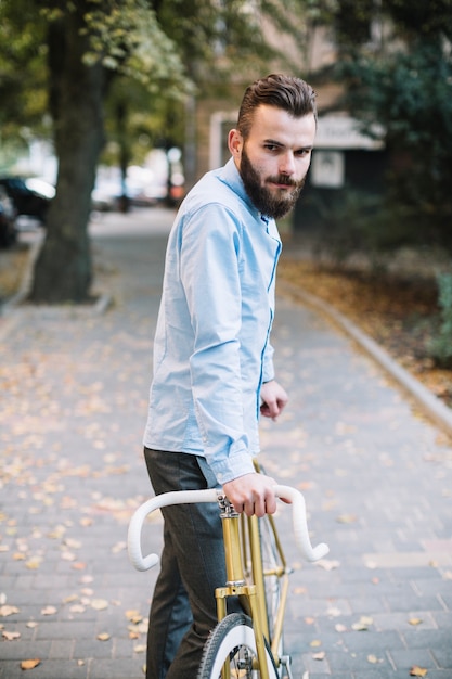 Mann mit dem Fahrrad, das Kamera betrachtet