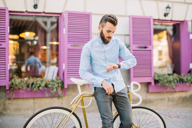 Mann mit dem Fahrrad, das Uhr betrachtet