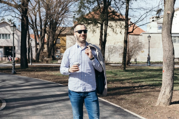 Kostenloses Foto mann mit dem heißen getränk, das auf straße geht