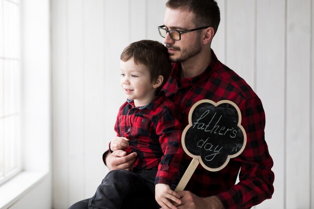 Mann mit dem Sohn, der aus Fenster am Vatertag heraus schaut