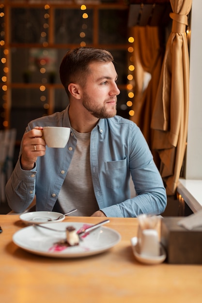 Kostenloses Foto mann mit dem tasse kaffee, der weg schaut