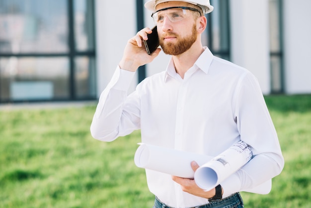 Mann mit den Entwürfen, die auf Smartphone sprechen