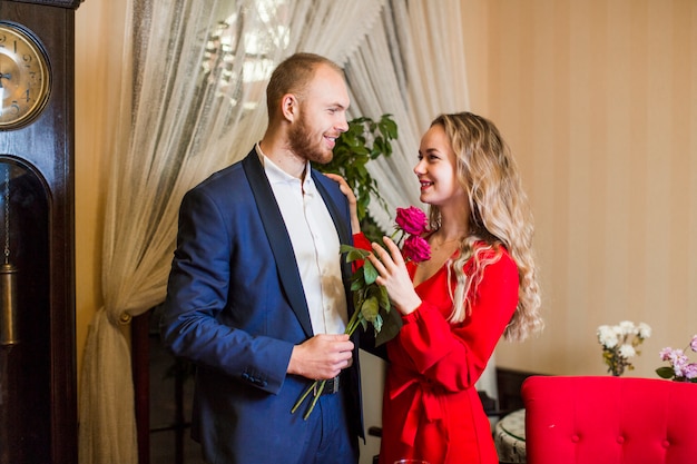 Mann mit den Rosen, die Frau im Restaurant umarmen