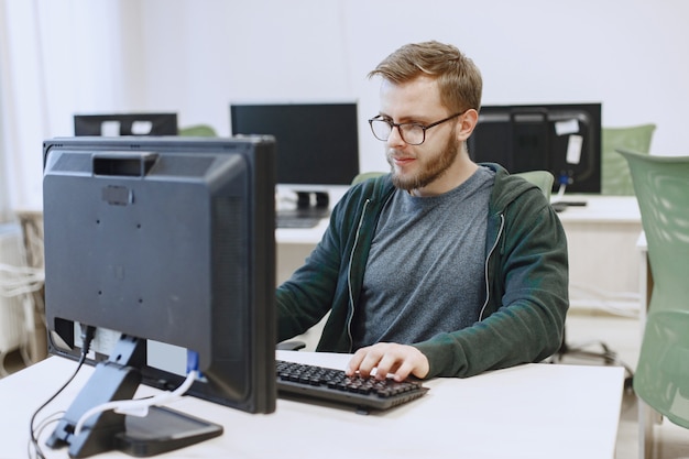 Mann mit der Brille. Student im Informatikunterricht. Person benutzt einen Computer.