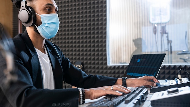 Kostenloses Foto mann mit der medizinischen maske, die an einem radiosender arbeitet