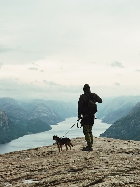 Mann mit einem Hund steht vor schöner Landschaft