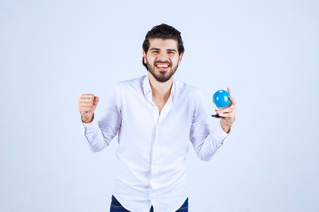 Mann mit einem Mini-Globus, der seine Faust zeigt