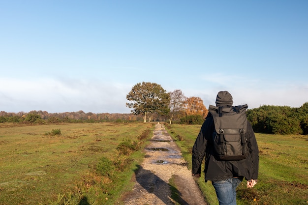 Mann mit einem Rucksack, der durch einen Weg in einem Feld geht