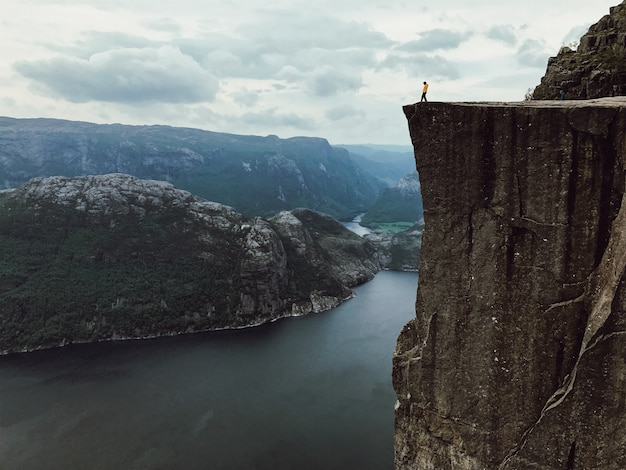 Kostenloses Foto mann mit einer gelben jacke posiert auf der oberseite des felsens